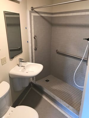 A spacious accessible bathroom with a shower and sink.