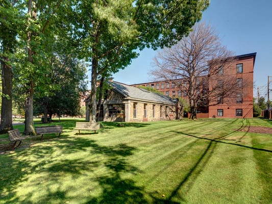 Exterior view of Robinson Cuticura Mill Apartments with lawn and trees
