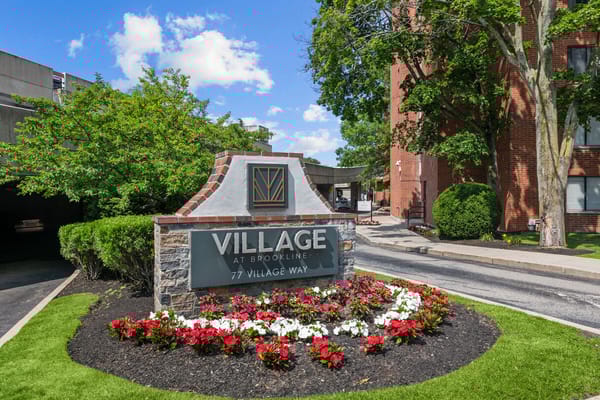 Sign for Village At Brookline with flowers and greenery