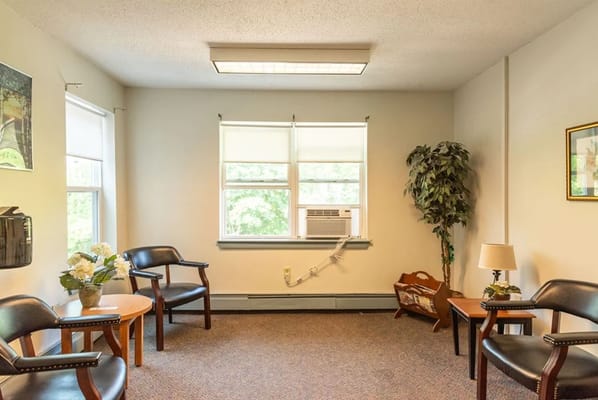 Lounge area with chairs, small tables, and a plant.
