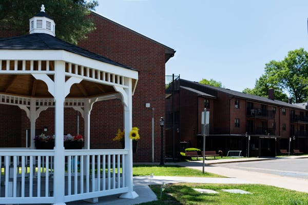 A white gazebo with flowers next to brick apartment buildings