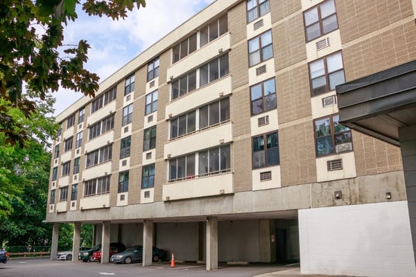 Exterior of Canterbury Arms Apartments building with parking area.