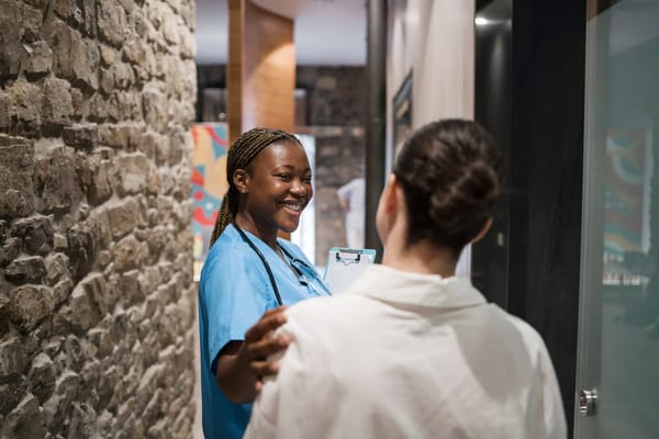 A smiling healthcare worker talks with a resident in a hallway.