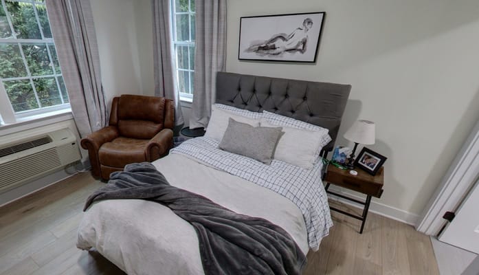 Cozy bedroom with a bed, armchair, and natural light.