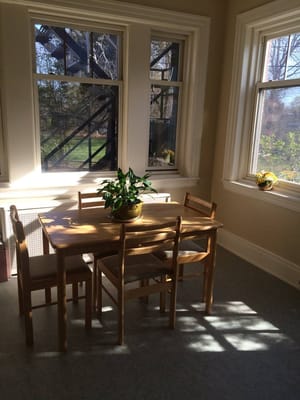 Bright common area with a table and chairs by large windows