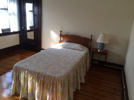 A cozy bedroom with a bed, lamp, and wooden floor