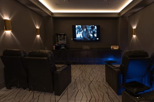 Cozy theater room with reclining chairs and a movie screen