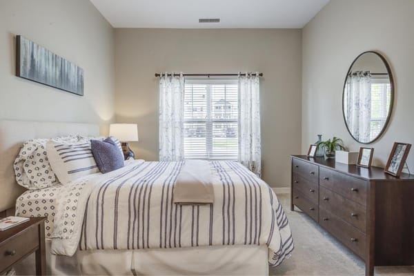 A well-decorated bedroom with a bed, dresser, and natural light