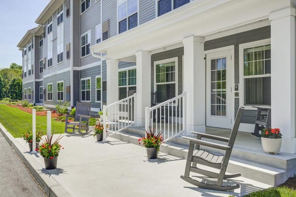 Porch area with rocking chairs and flower pots at senior living facility