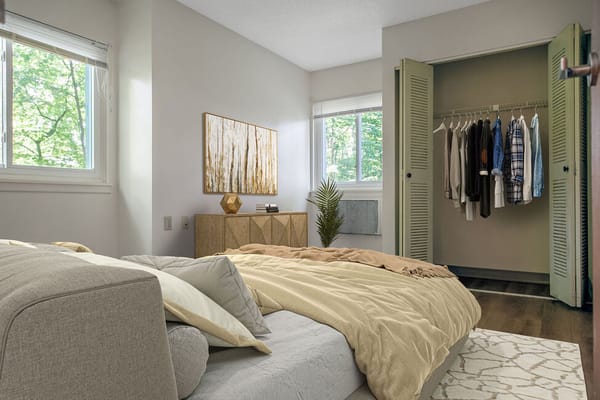 Bright bedroom with a bed, decorative artwork, and closet space.