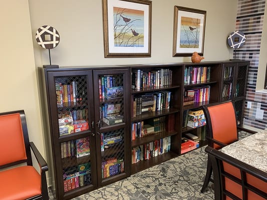 Library shelves filled with books and games in a senior living facility