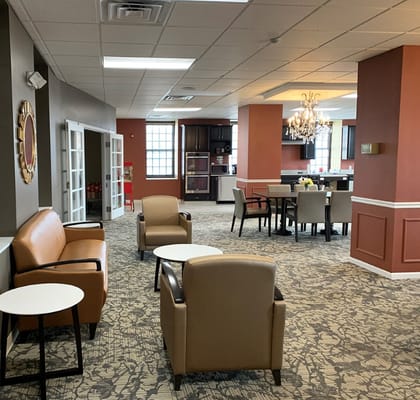 A spacious common area with seating and a kitchen in Jennings Senior Living.