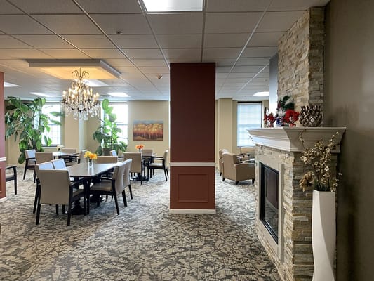 Spacious dining area with tables and chairs, plants, and a fireplace