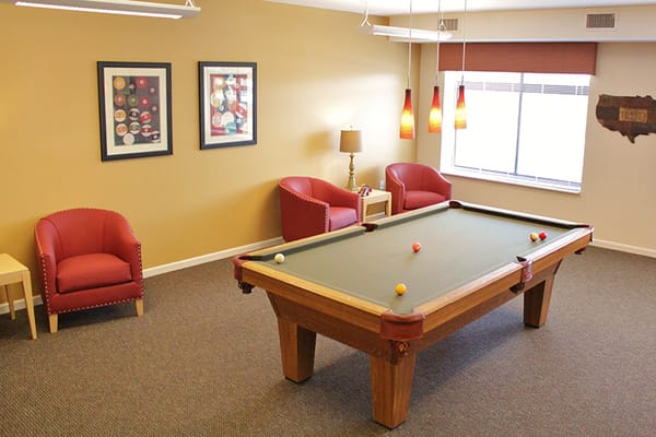 Billiards table with red chairs in a lounge area