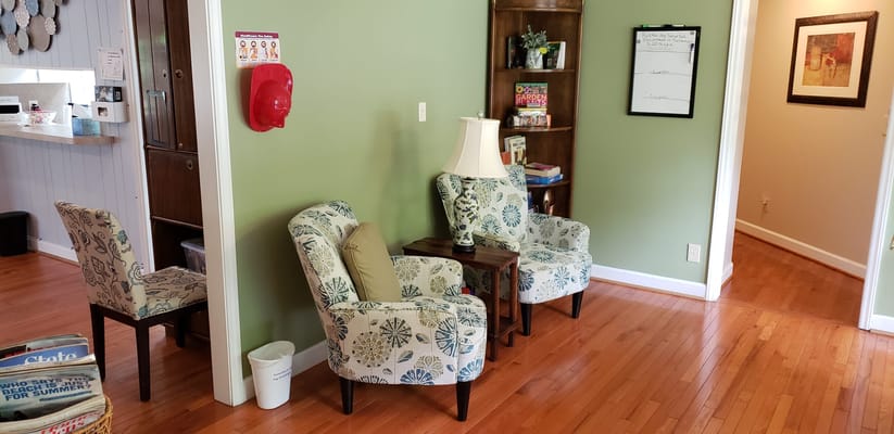 A cozy living area with patterned chairs, a side table, and a bookshelf.