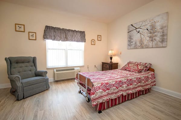 A cozy bedroom with a bed, chair, and lamp.