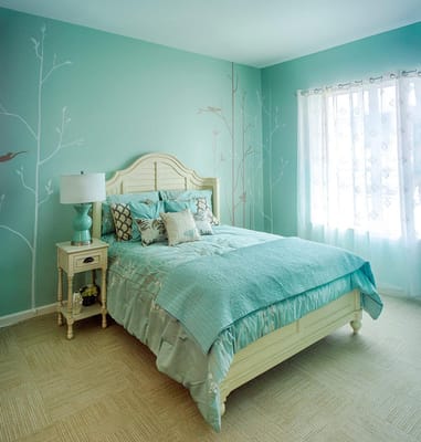 A beautifully decorated bedroom with teal walls, a queen bed, and natural light.