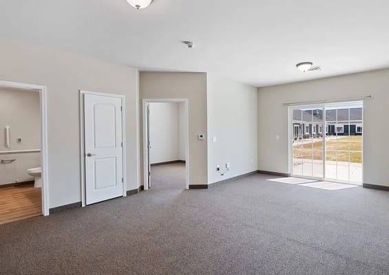 Bright living area with carpet and access to the outdoors.