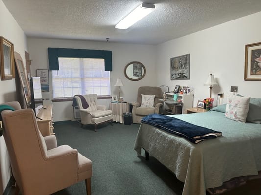 Cozy private room with a bed, armchairs, and a window