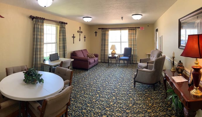 A common area featuring seating, decorative lamps, and a table with chairs at The Brentwood Senior Living.