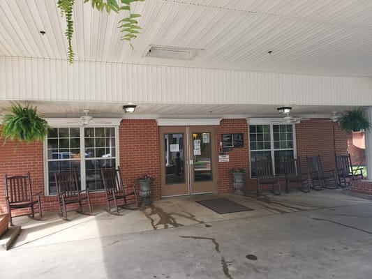 Entrance area with rocking chairs and potted plants at Dermott City Nursing Home