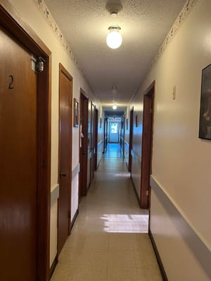 View of a hallway with numbered doors and overhead lights.