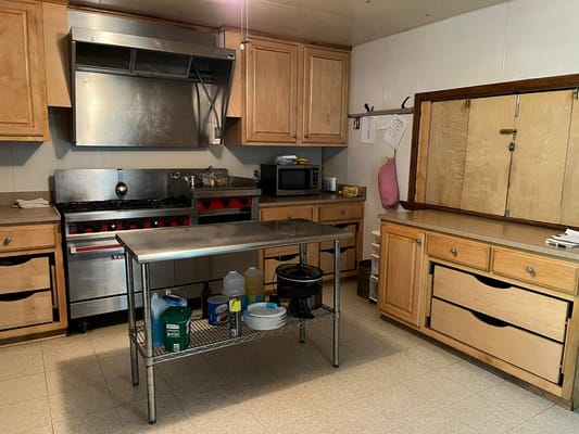 Commercial kitchen with stainless steel appliances and wooden cabinets.