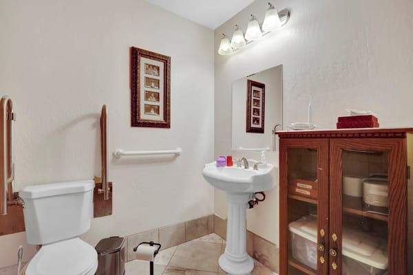 Brightly lit accessible bathroom with grab bars and a sink.