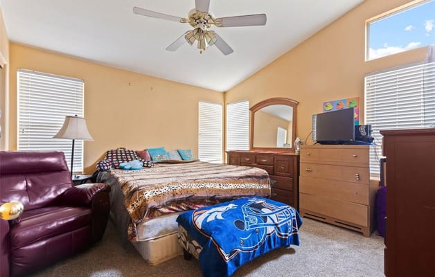 A well-furnished bedroom with a bed, dresser, and seating area.