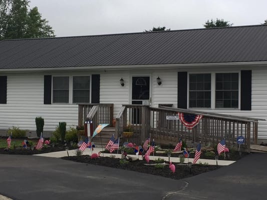 Entrance of a senior living facility with flags and decorations.