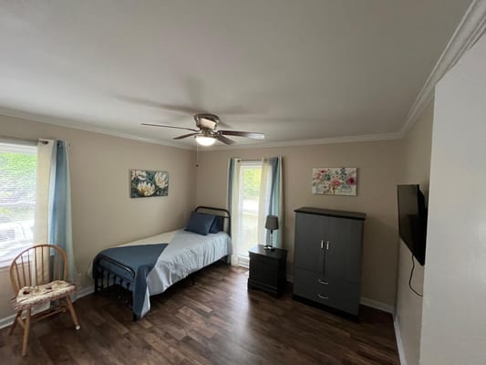 A private resident room featuring a bed and dresser