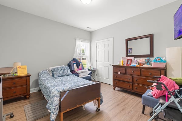 Private bedroom featuring a bed, dresser, and seating area.