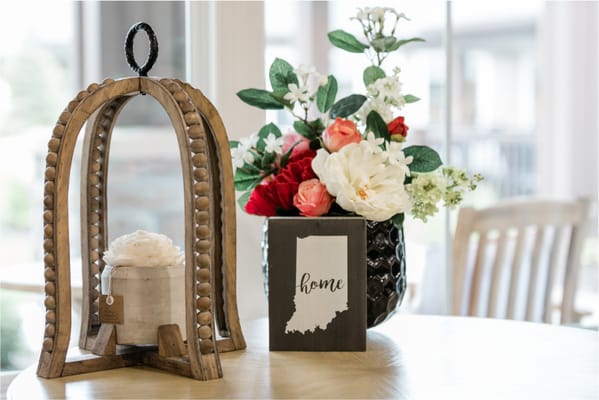 Stylish decorative items on a table, including a lantern, floral arrangement, and a sign that says 'home'