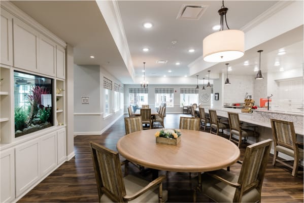 Bright dining room with round table and seating at Grand Brook Memory Care.