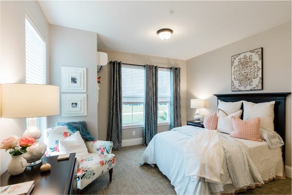 A nicely decorated resident room with a bed and seating