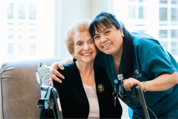 A resident posing happily with staff in a common area