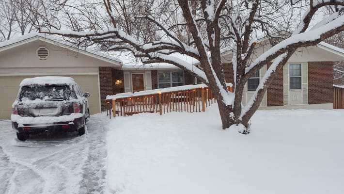 Entrance of Clermont Assisted Living covered in snow with a car parked nearby.