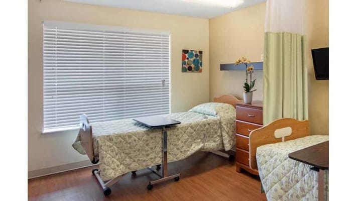 A private resident room with two beds and a window