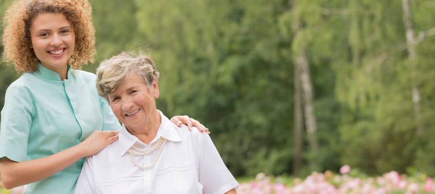 Caregiver and resident smiling in a garden setting