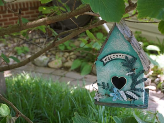 A decorative birdhouse hanging in a garden