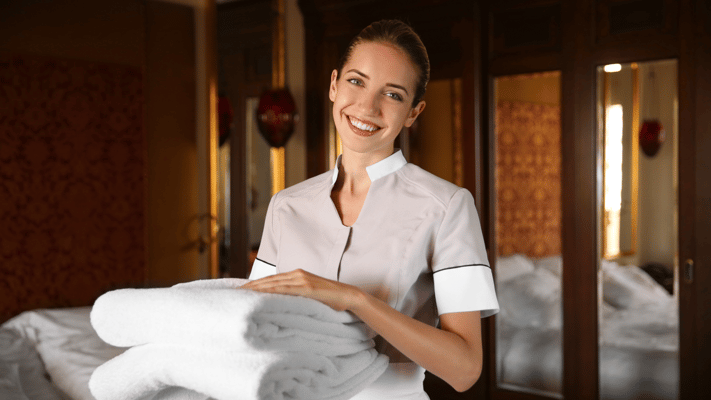 Staff member smiling while holding towels in a clean room