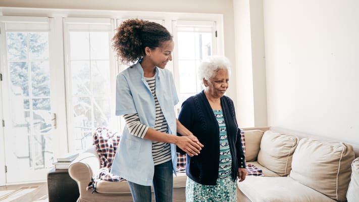 A staff member assisting a resident in a cozy living room.