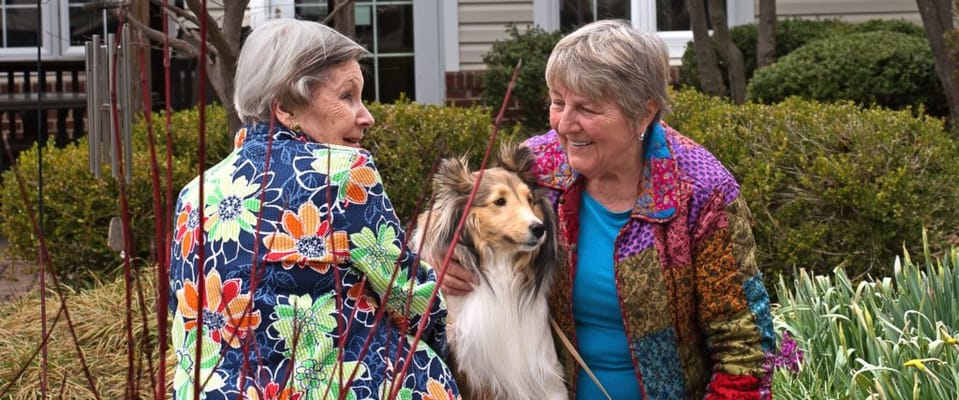 Two residents enjoying a moment outdoors with a dog
