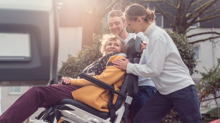 A resident enjoying time outdoors with two staff members