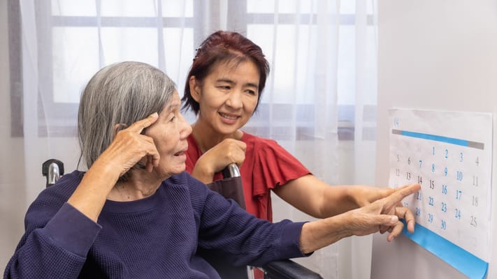 Caregiver assisting resident with a calendar in a room