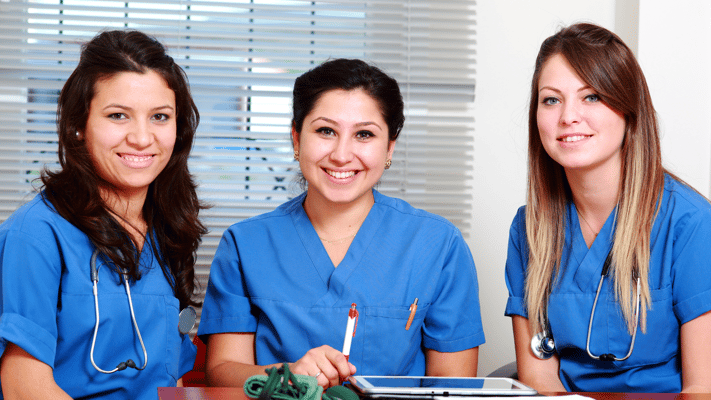 Three healthcare professionals smiling together indoors