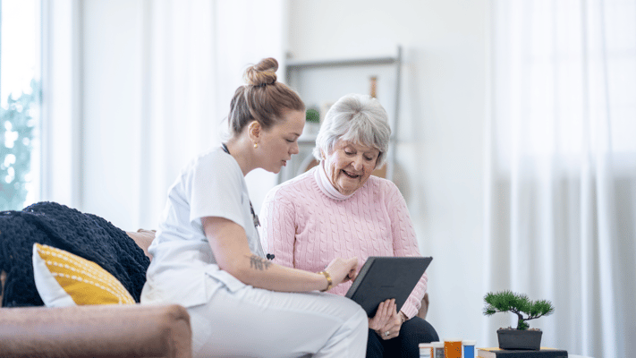 Staff assisting a resident with a tablet in a cozy setting