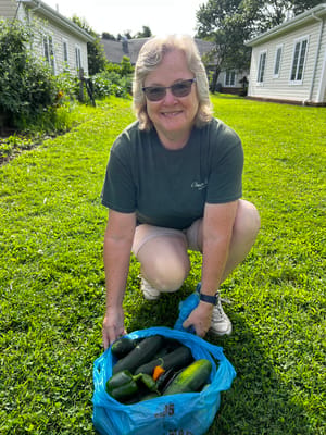 A staff member holds a bag of fresh vegetables in a garden