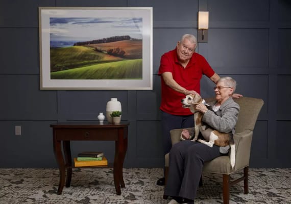 Residents interacting with a dog in a cozy lounge
