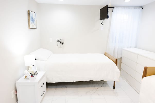 A private resident room with a bed and dresser